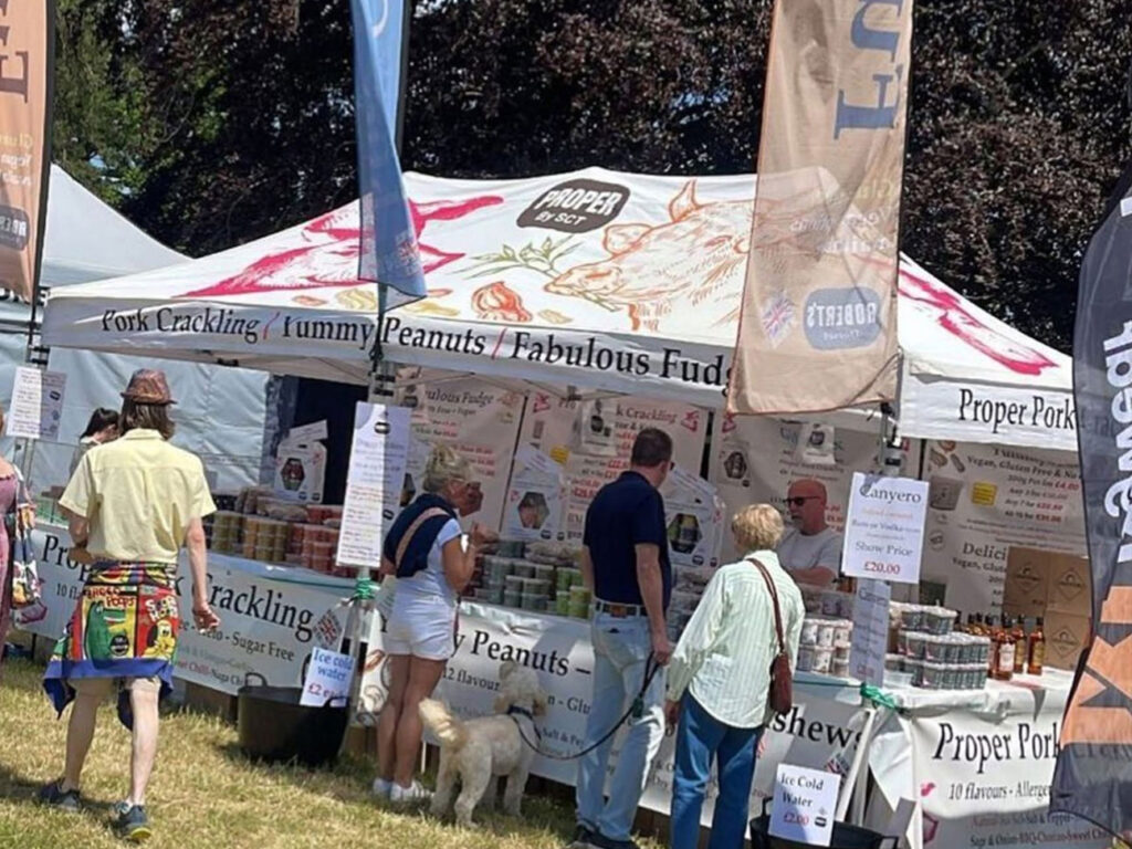 An independent street food trader using a Surf & Turf custom printed gazebo and flags at an outdoor festival.
