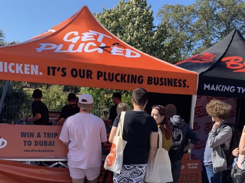 Custom printed gazebo in bright orange for Get Plucked street food trader at a busy UK outdoor event, showcasing high-visibility event branding.